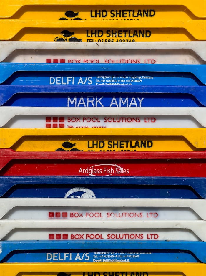 Vibrant fishing crates stacked outdoors, showcasing commercial branding in Aldeburgh, UK.